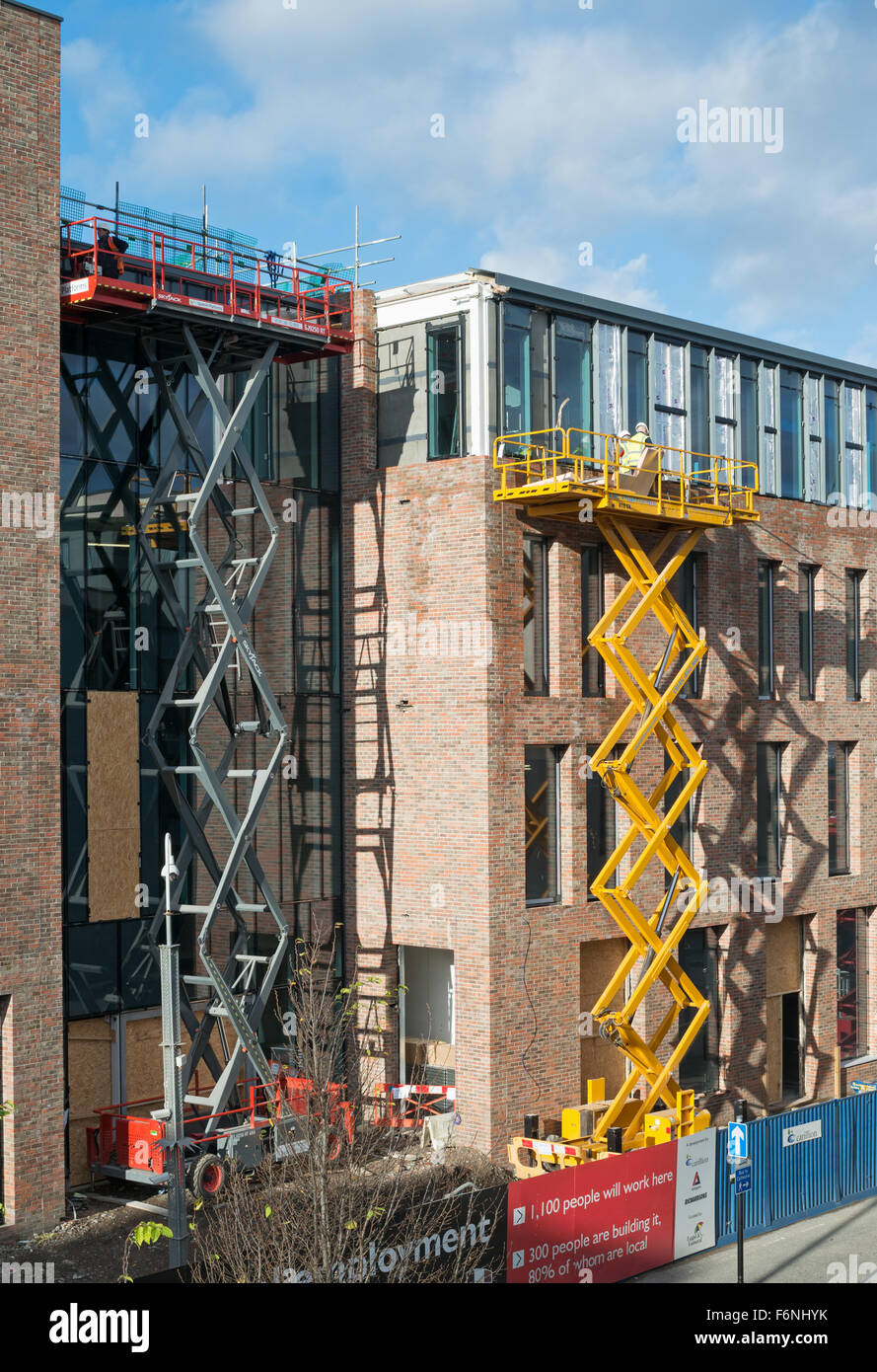 Builders using two scissor lift powered access platforms during construction work, Durham City, Co. Durham, England, UK Stock Photo