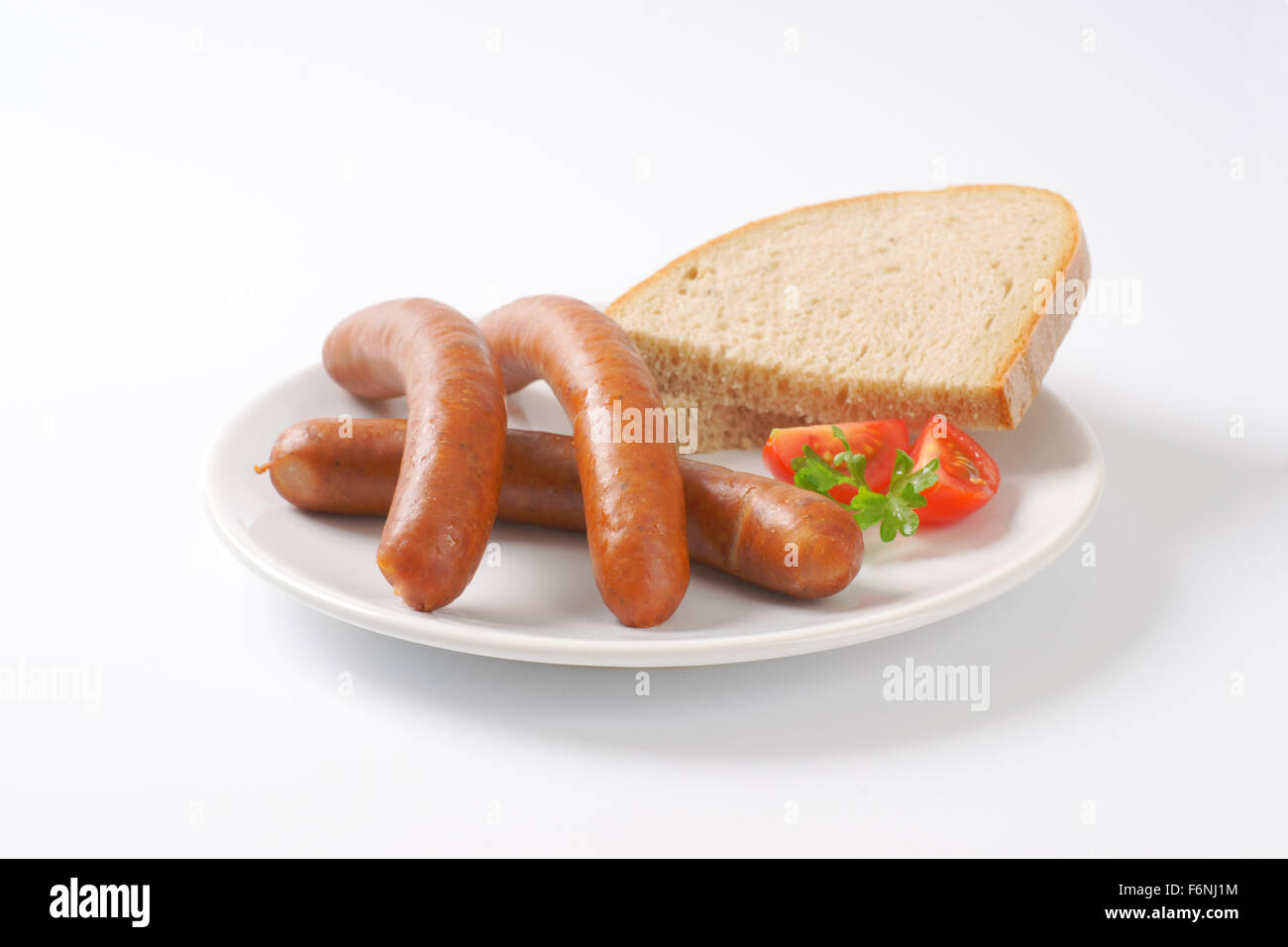 hot frankfurter sausages and slice of bread on white plate Stock Photo