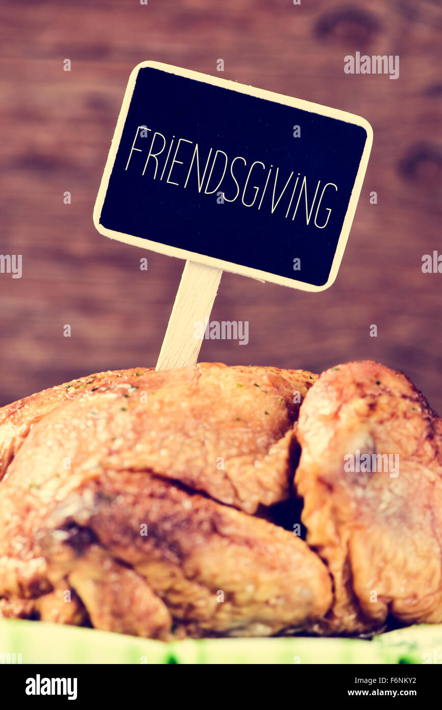 closeup of a roast turkey in a tray with vegetables with a black label with the text friendsgiving, gathering thanksgiving with Stock Photo
