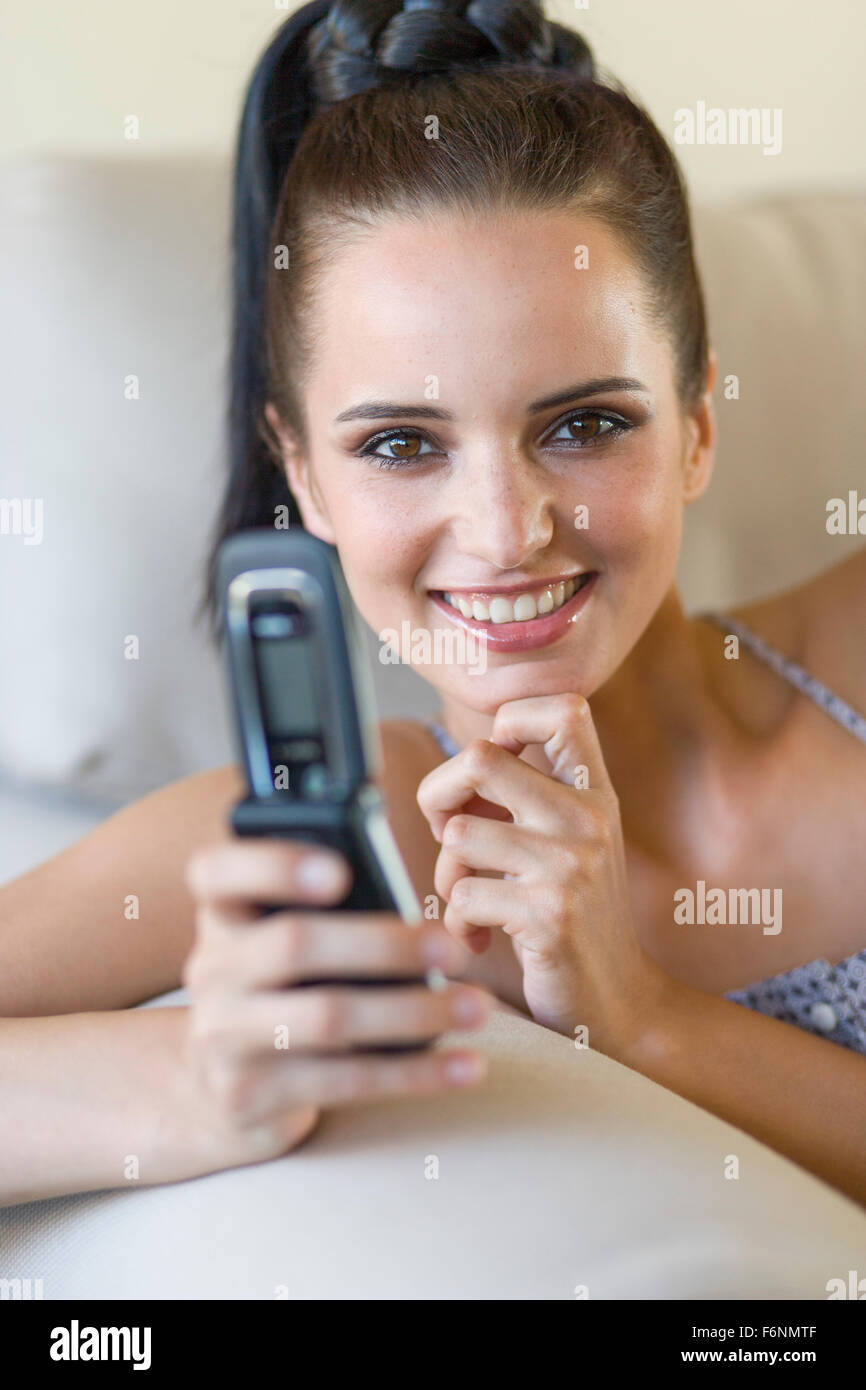 Young woman with cellphone on couch Stock Photo