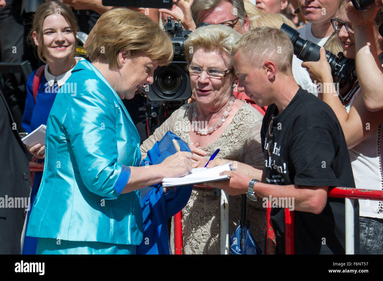 FILE - An archive picture dated 25 July 2015 shows German Chancellor Angela Merkel (CDU, L) signing her autograph during the opening of the Bayreuth Festival in Bayreuth, Germany. Photo: Tobias Hase/dpa Stock Photo