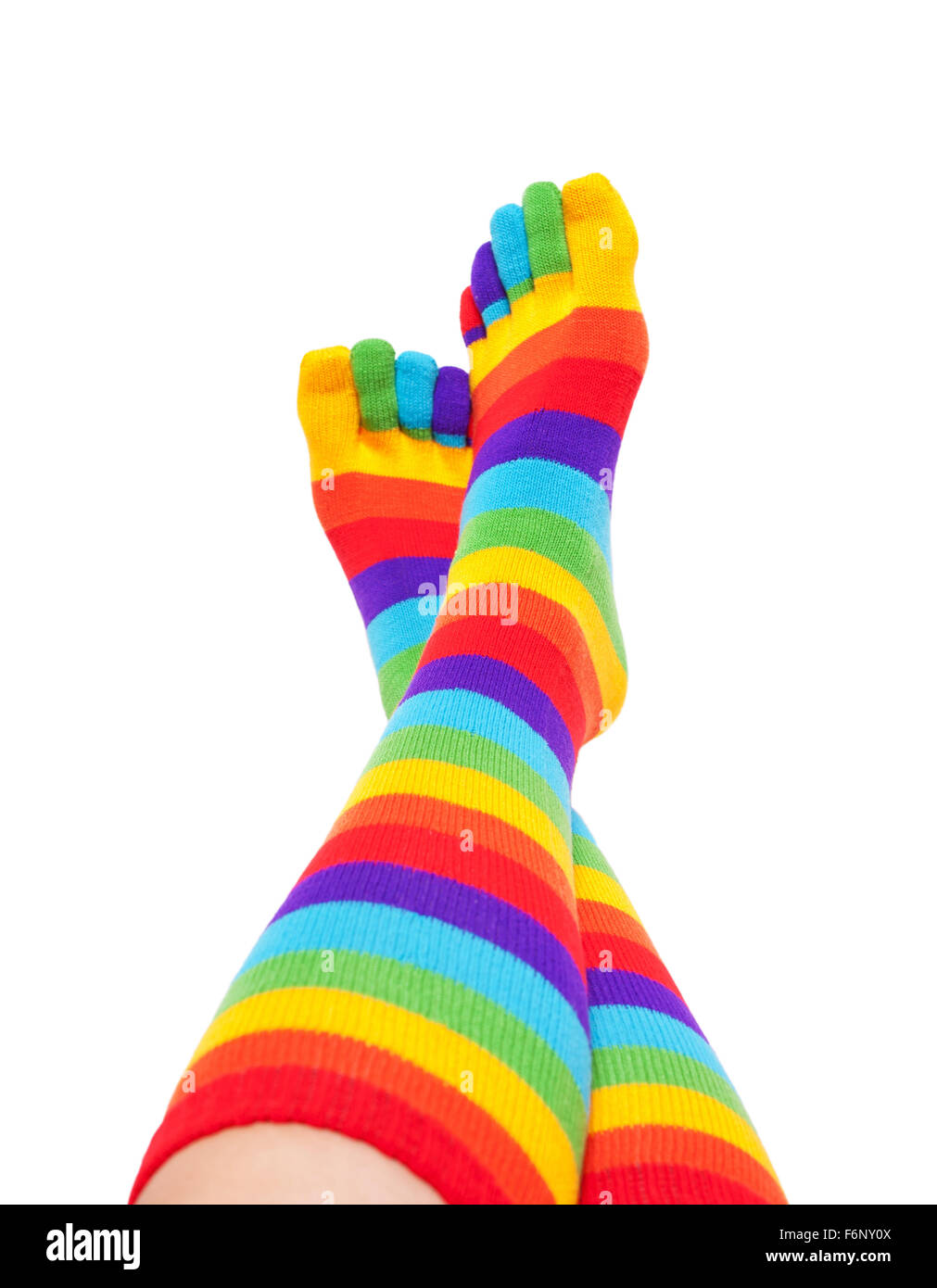 Female feet and legs in colorful striped rainbow socks raised up and relax. Isolated on white background Stock Photo
