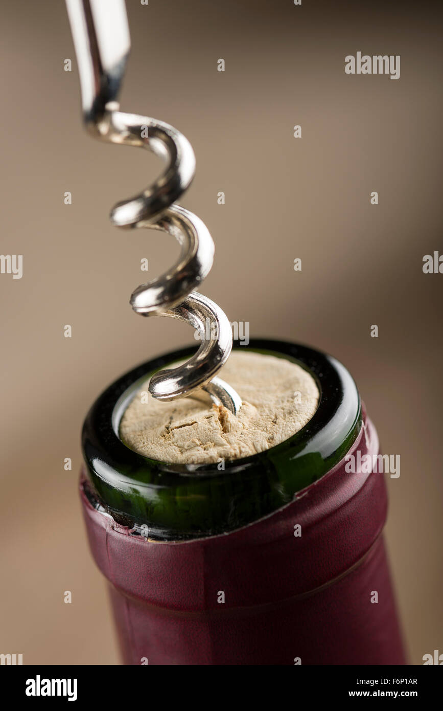 corkscrew inserted on cork into red wine bottle, closeup. Stock Photo
