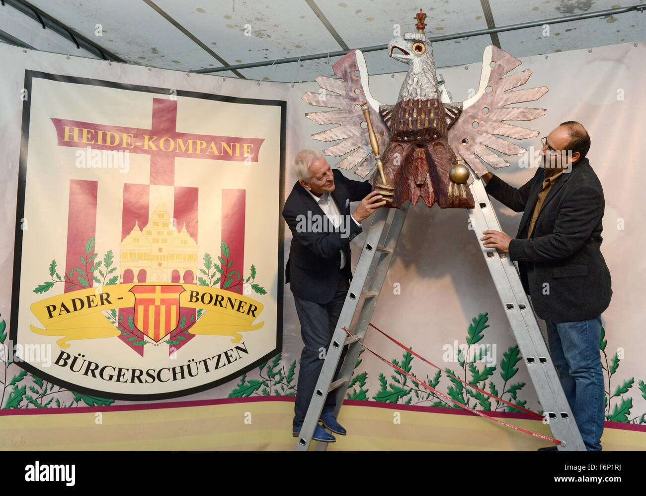 Paderborn, Germany. 16th Sep, 2015. The chairman of the local marksmenship association 'Paderborner Buergerschuetzen', Heinz-Josef Noetges (l) and Gabro Barsoum (r) from Syria attach a marksmenship eagle to the festival tent of the association in Paderborn, Germany, 16 September 2015. Photo: Caroline Seidel/dpa/Alamy Live News Stock Photo