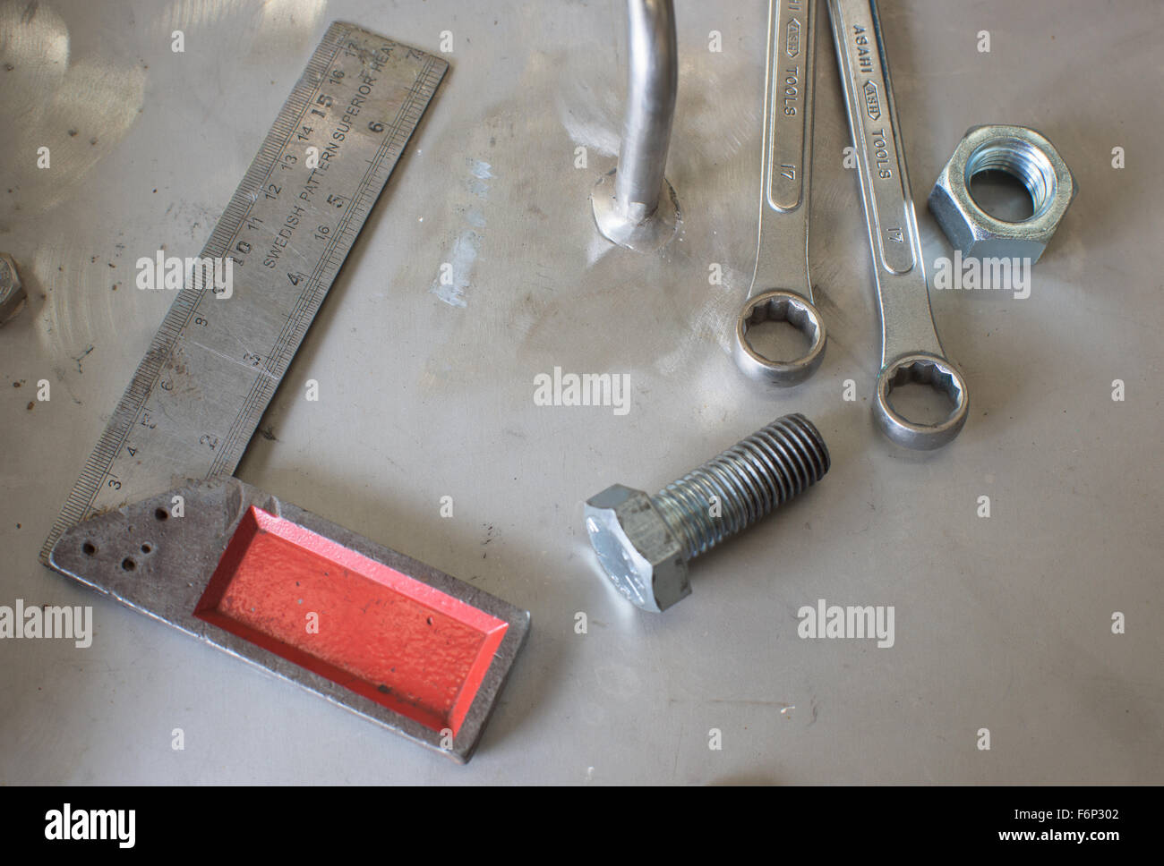 Assorted metal tools on a steel plate at an industrial workshop. Stock Photo