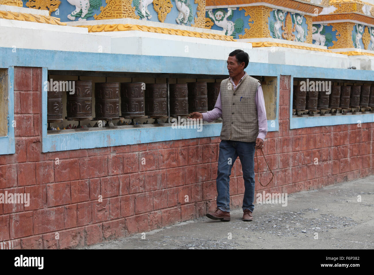 SPITI VALLEY - Devotee spinning prayer wheels outside Kaza Monastery in Kaza village, Himachal Pradesh, India Stock Photo