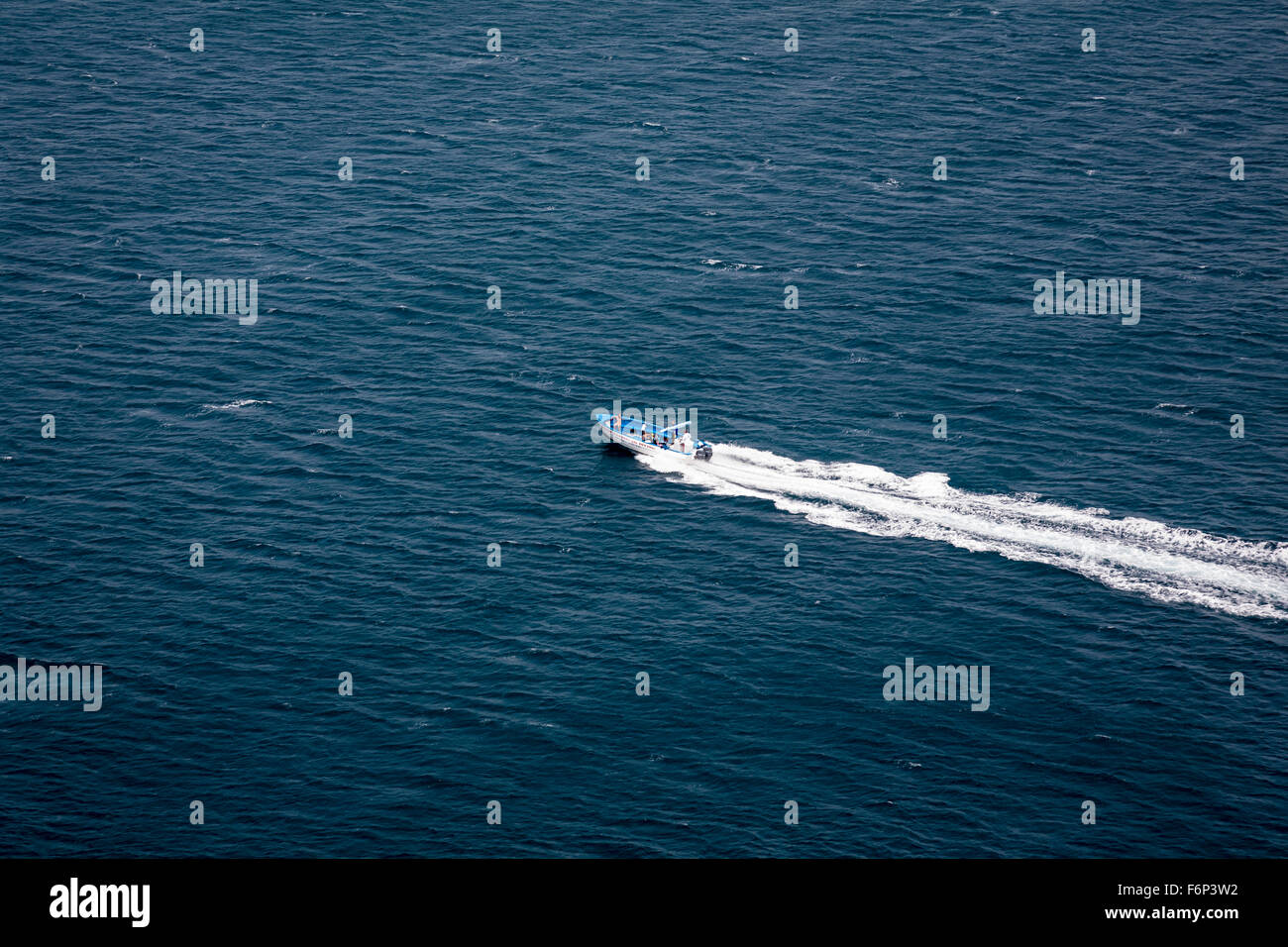 Viewed from above, a speed boat creates a dramatic white wash across a turquoise tropical sea. Stock Photo