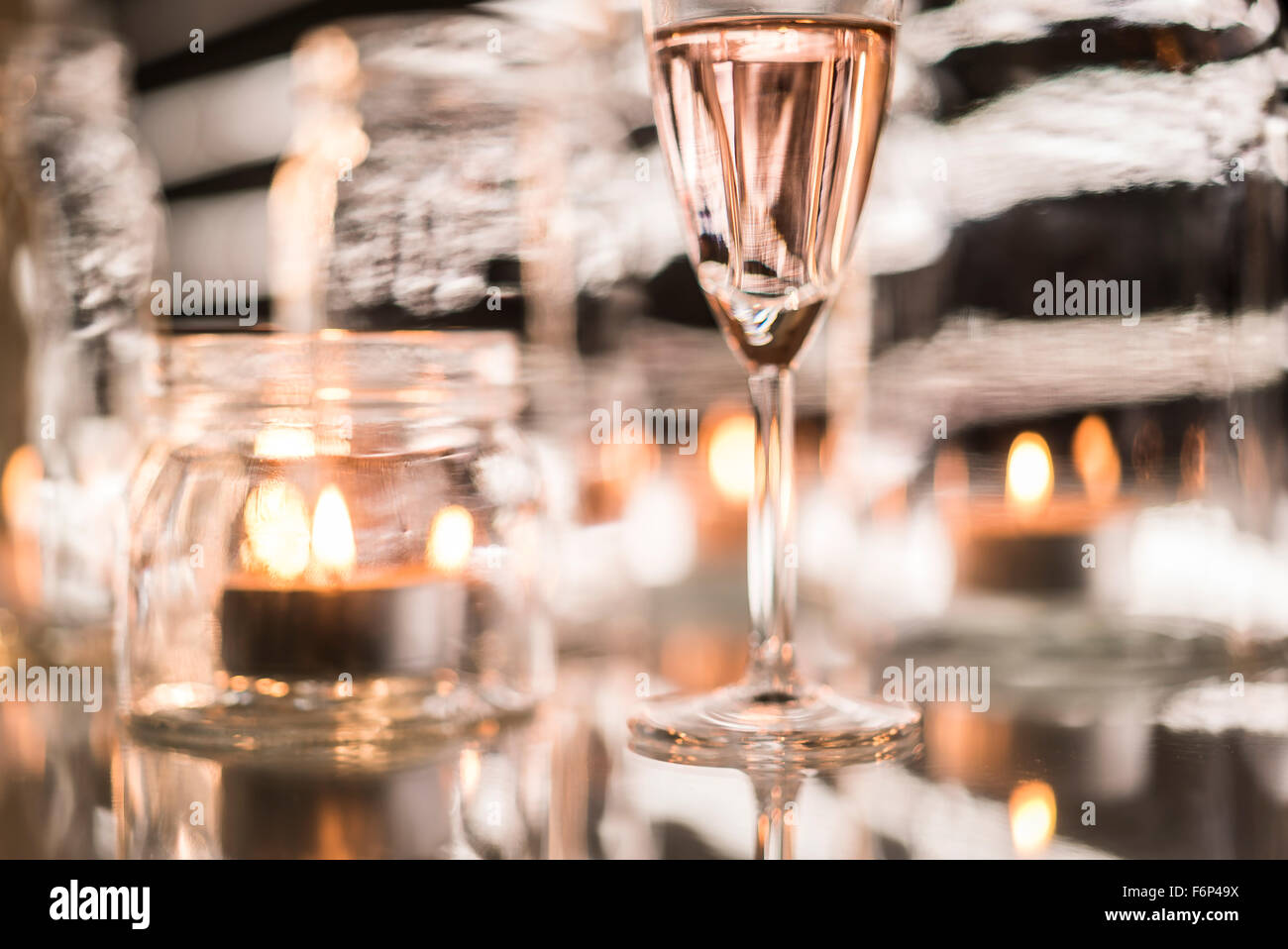 White wine glass and candles in glass jars Stock Photo