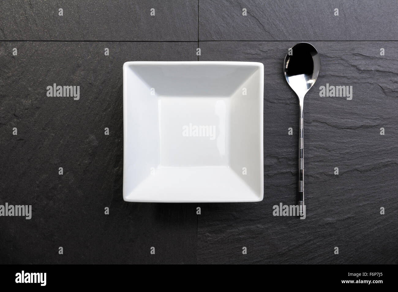 Overhead view of white square bowl and spoon. Stock Photo