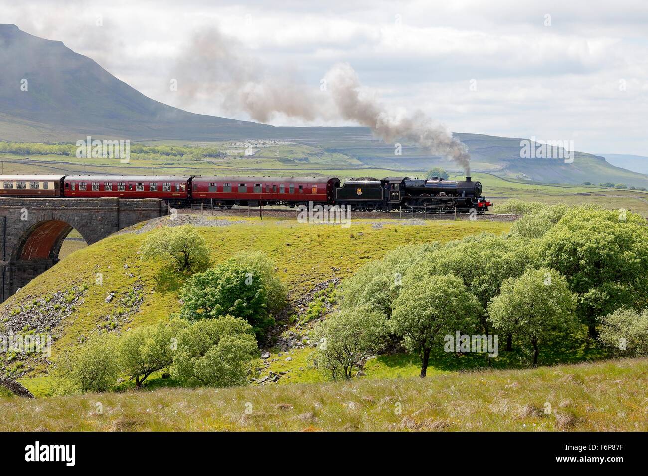 Ribblehead Viaduct. Steam train LMS Jubilee Class Leander 45690 after crossing the viaduct below Ingleborough hill. Stock Photo