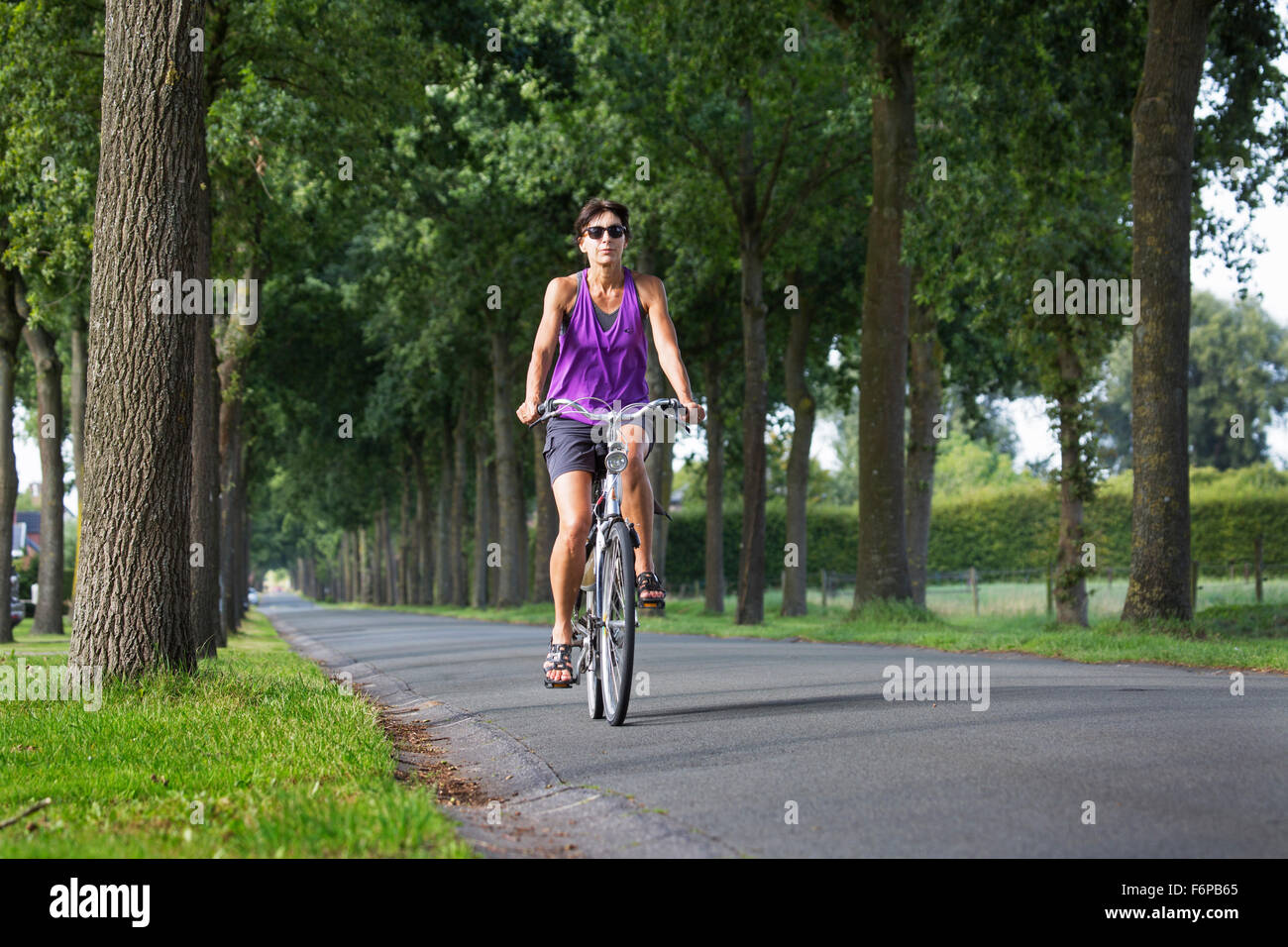 Woman on bicycle cycling through rural landscape in summer Stock Photo