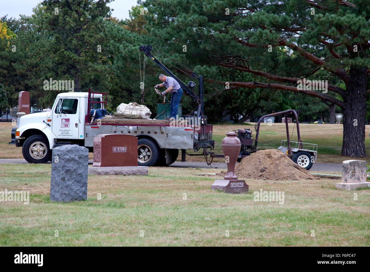 Gravedigger on his truck delivering vault to cemetery plot. Minneapolis