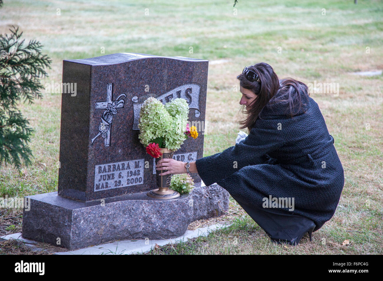 Daughter paying respects at her mothers grave site with a bouquet of flowers. Crystal Lake