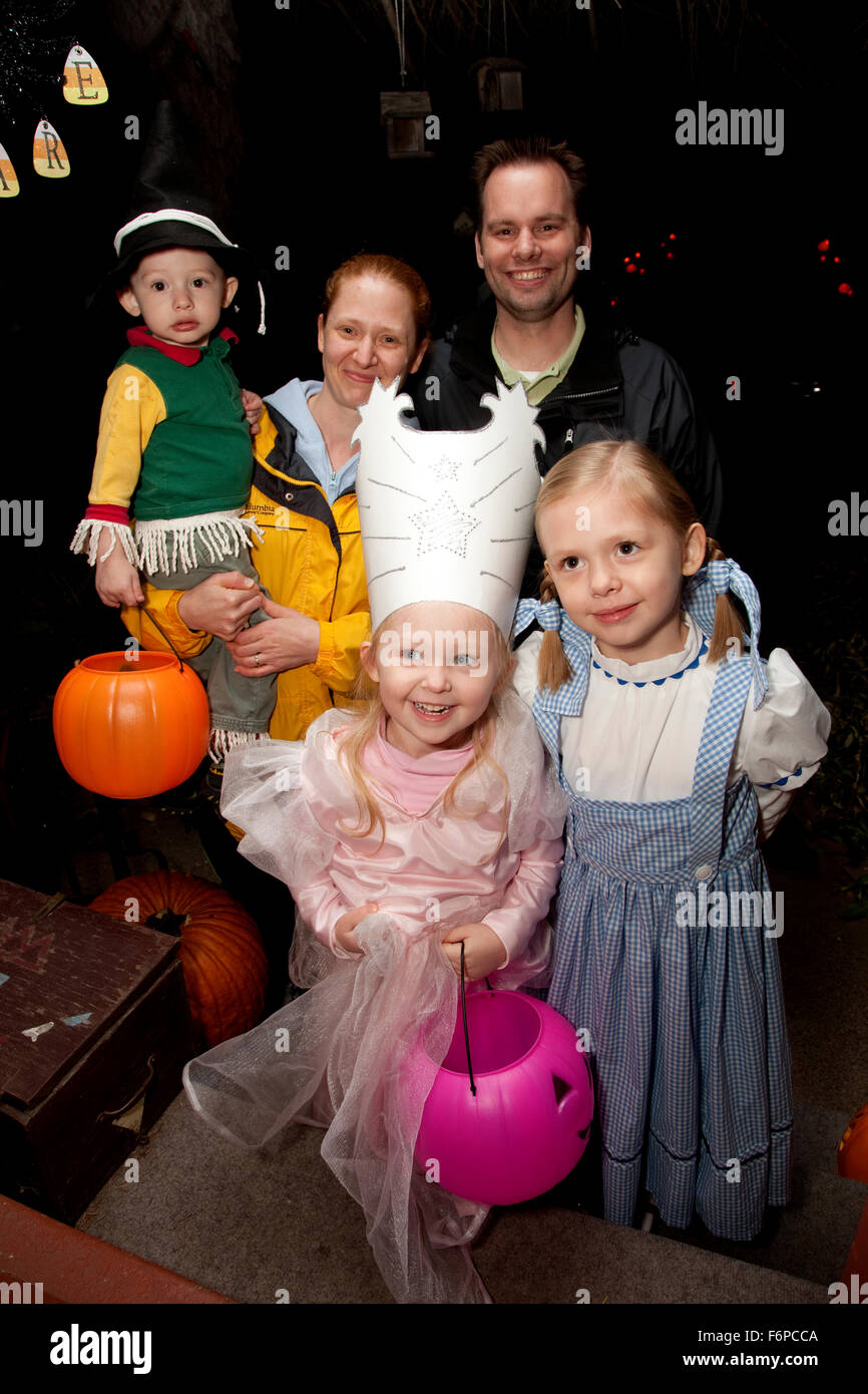 Family of Halloween trick or treaters in costume at front door with