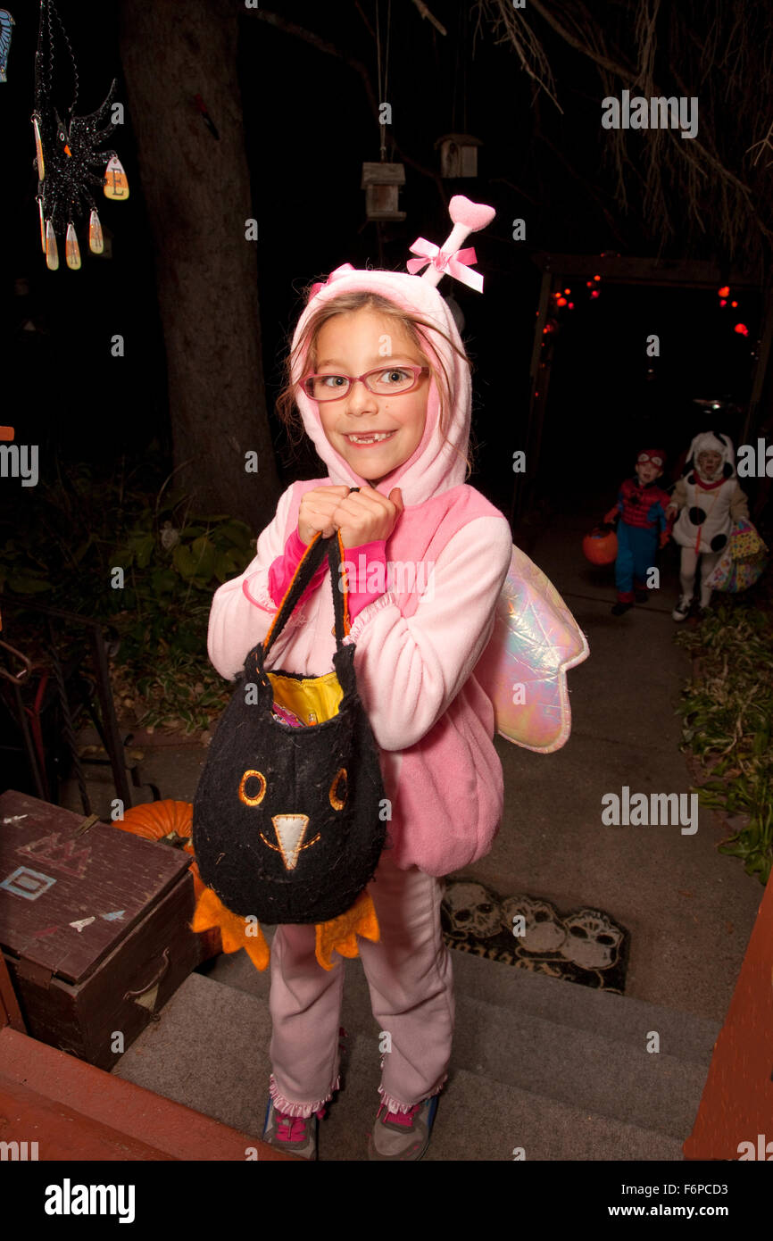 Costumed Halloween fairy with wings carrying an owl Jacko'lantern