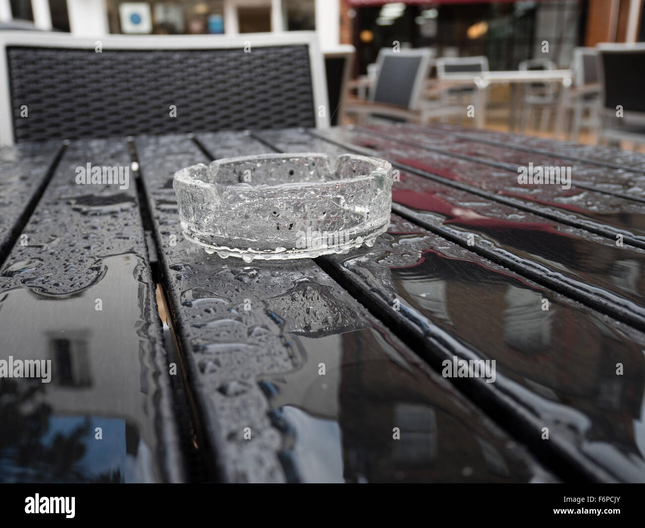 An ashtray on an empty pub outside table in the rain. Stock Photo