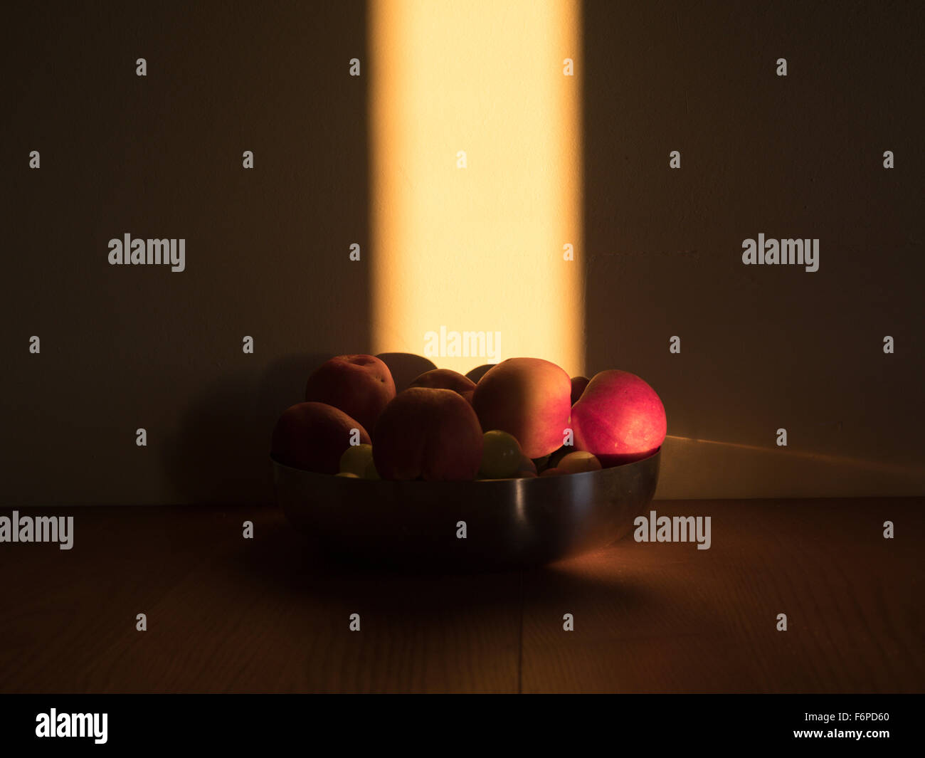 a still life of oranges and apples in a bowl lit by a shaft of sunligh to look like a painting Stock Photo