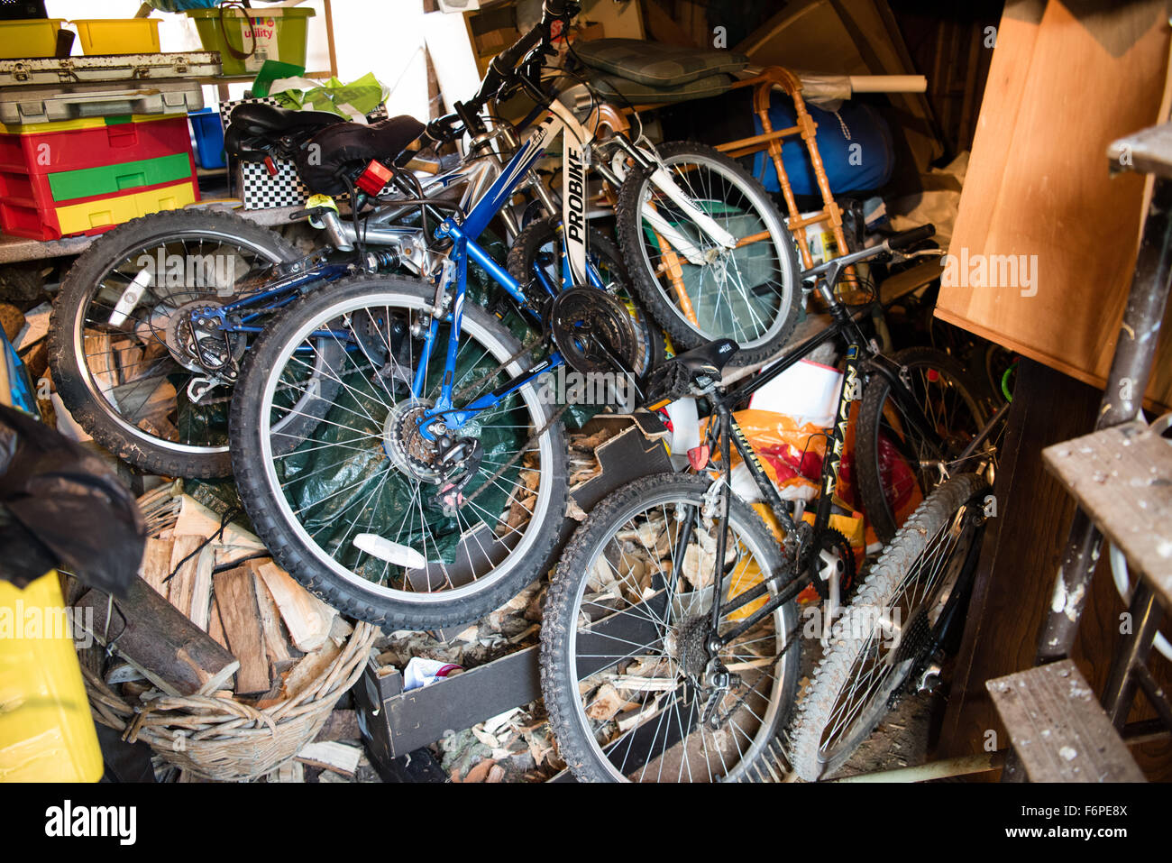 Inside a messy and cluttered wooden garage shed with tools, bikes and garden equipment piled up on uneven shelves in organised chaos Stock Photo