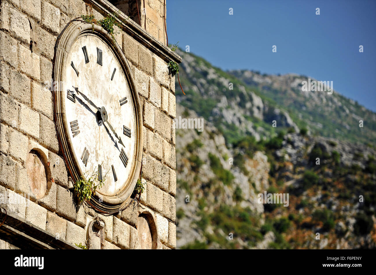 Old clock tower with vegetation growing on it in Kotor Stock Photo