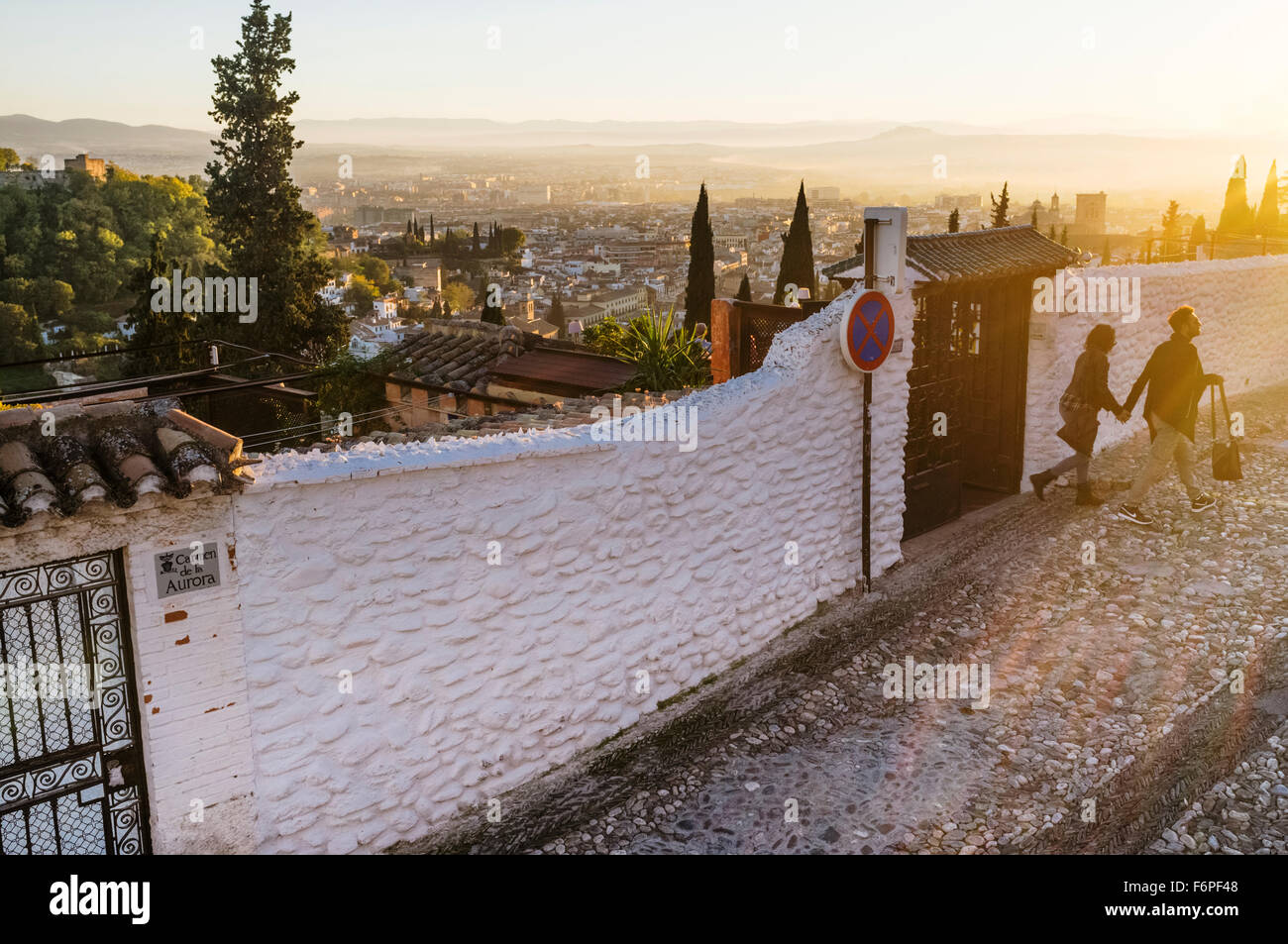 Couple walking at sunset through the alleys of the Moorish Albaicin quarter with Granada overview in background. Granada, Spain Stock Photo