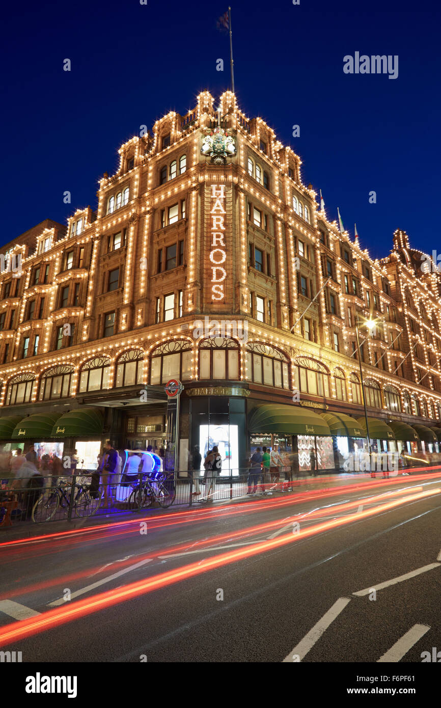 The famous Harrods department store illuminated at night with car passing lights in London Stock Photo