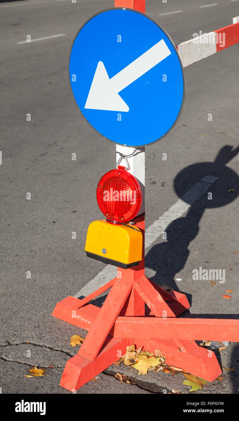 Roadsign with red light and white arrow in blue circle marks border of roadworks area Stock Photo
