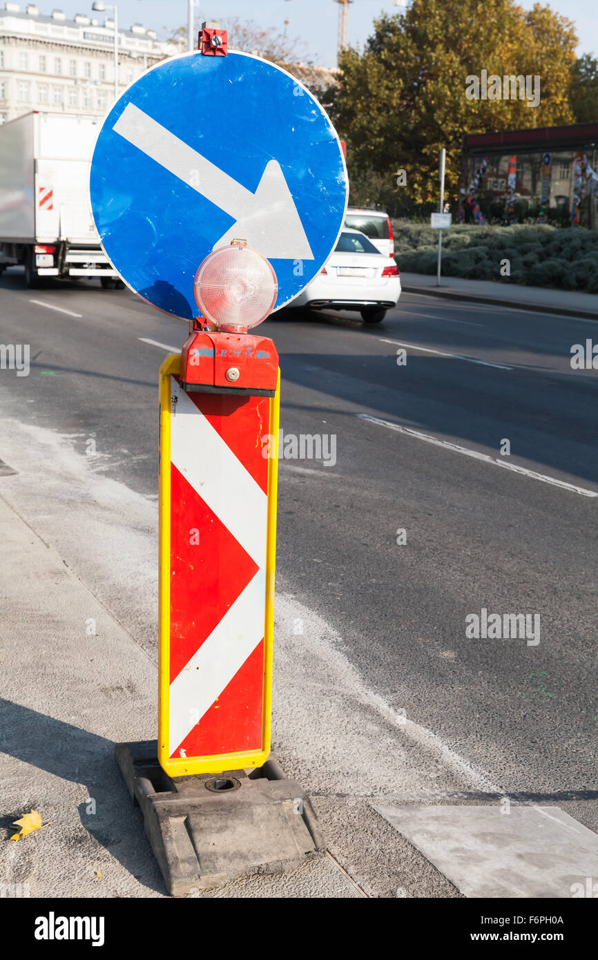 Roadsign with red light and white arrow in blue circle marks a border of roadworks area Stock Photo