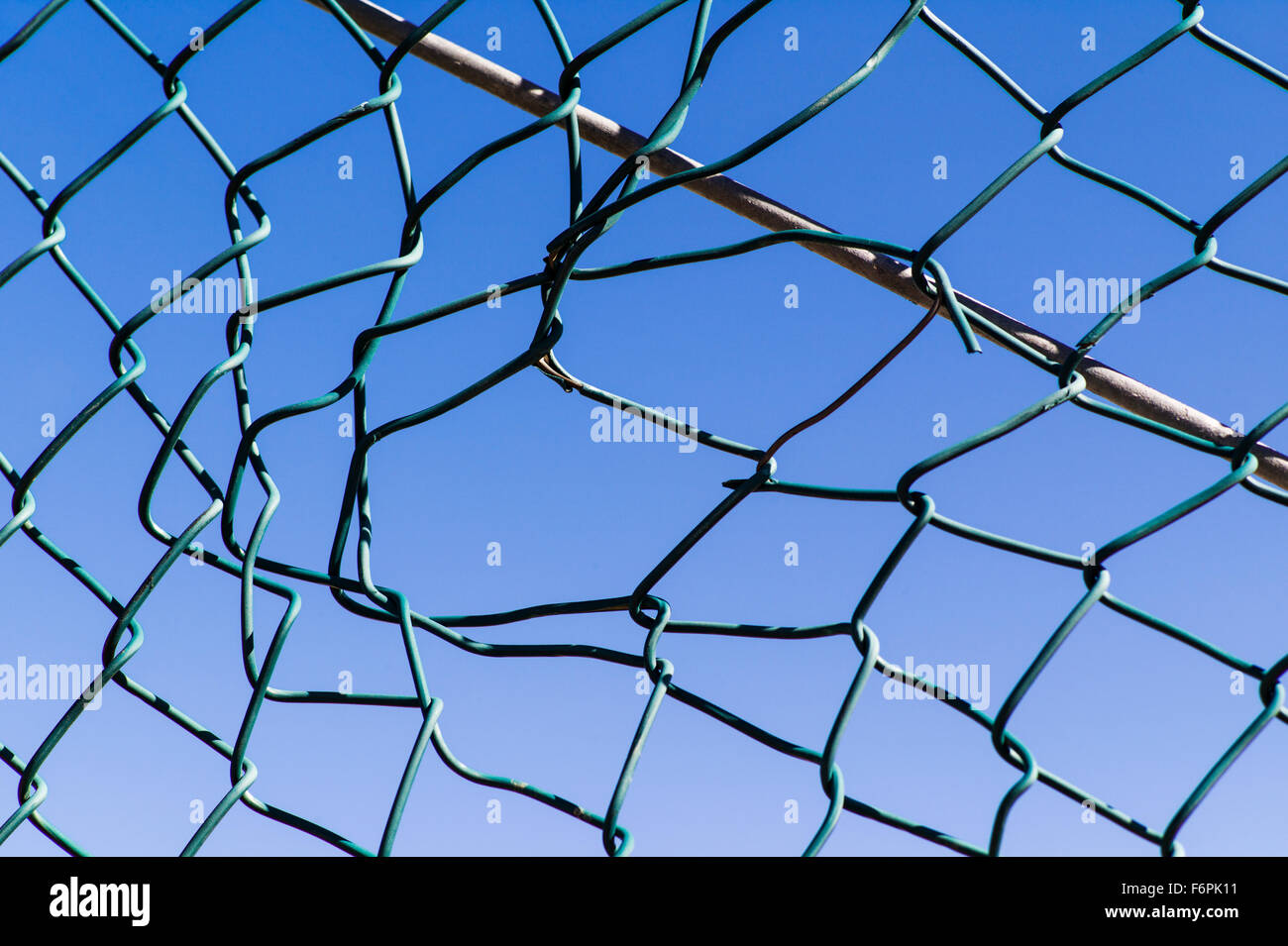 Torn hole in a wire mesh, hurricane, or cyclone steel fence Stock Photo