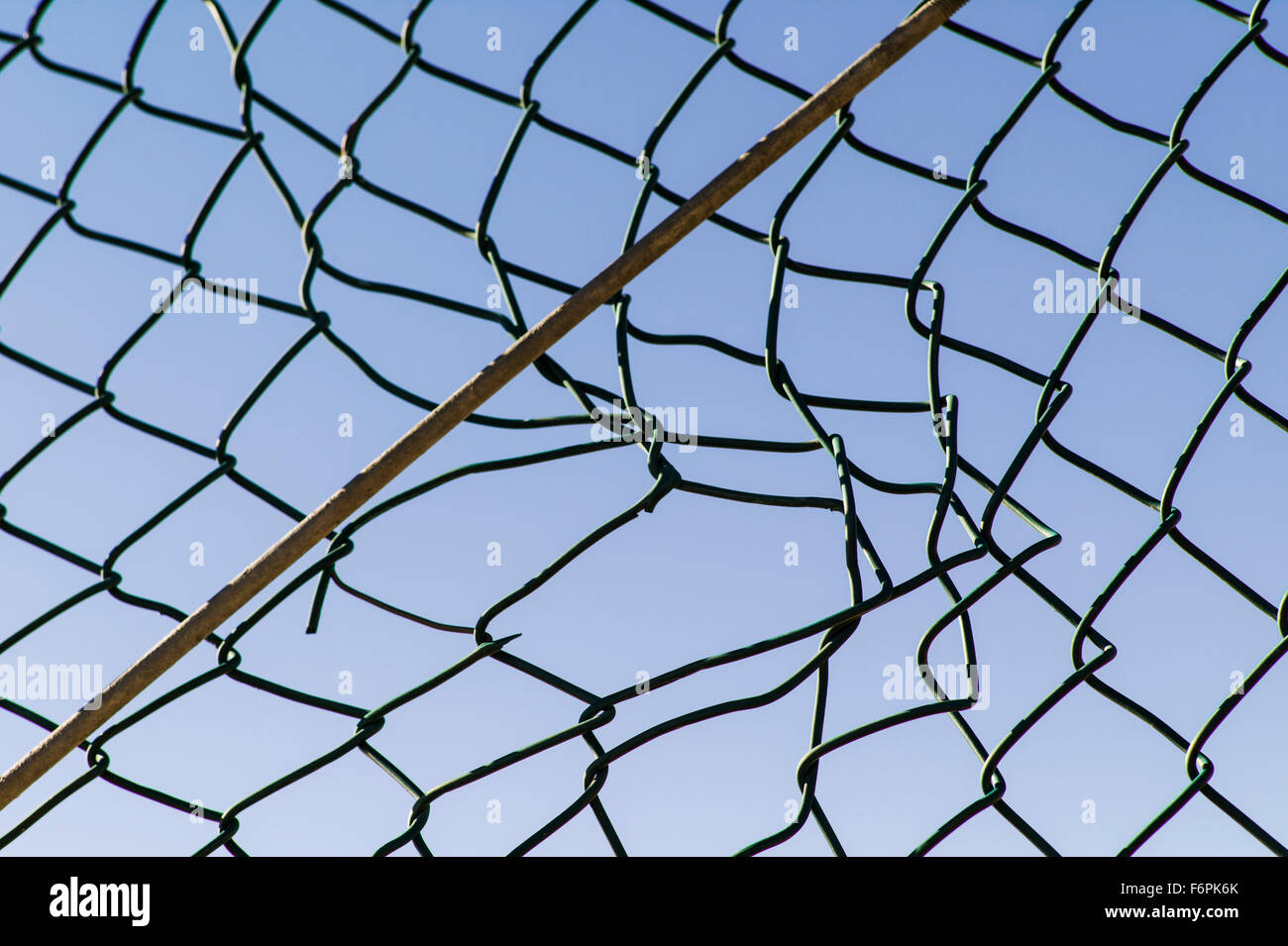 Torn hole in a wire mesh, hurricane, or cyclone steel fence Stock Photo