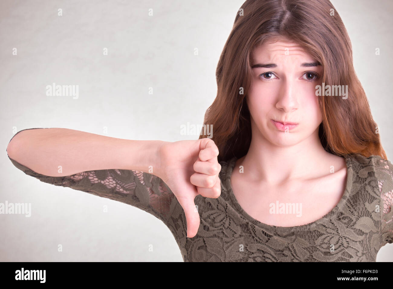 Woman showning negative feelings with her thumb down, isolated in grey Stock Photo