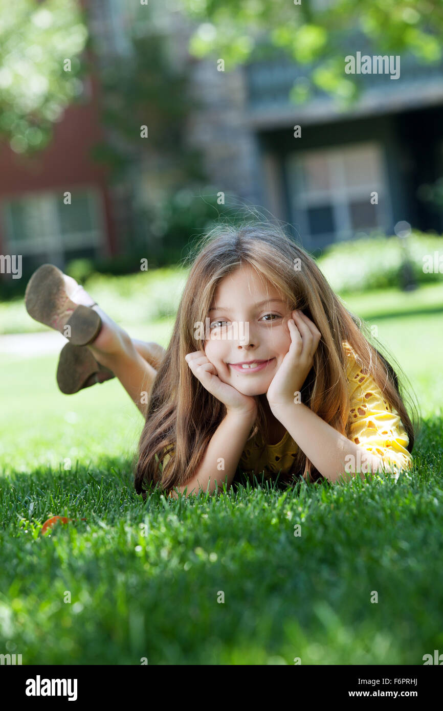 portrait of little girl laying on the grass in summer environment Stock ...
