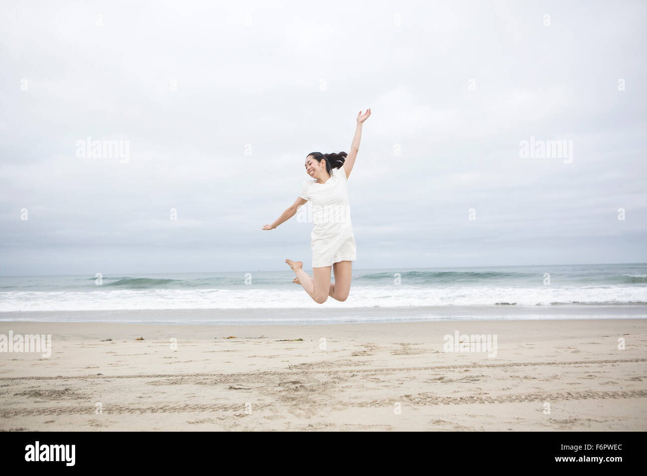 Woman jumping for joy on beach Stock Photo