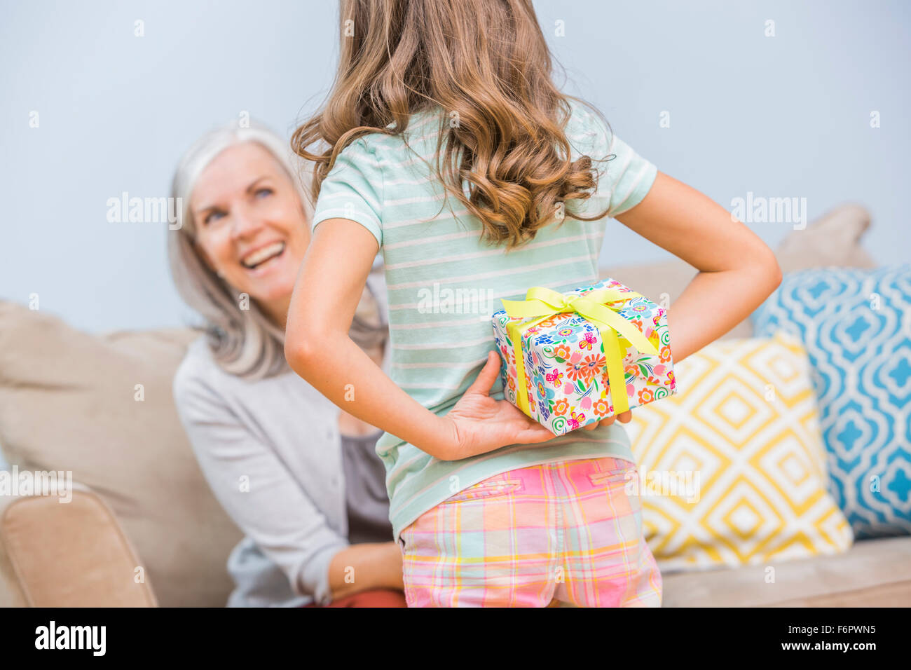 Caucasian girl hiding gift for grandmother behind back Stock Photo