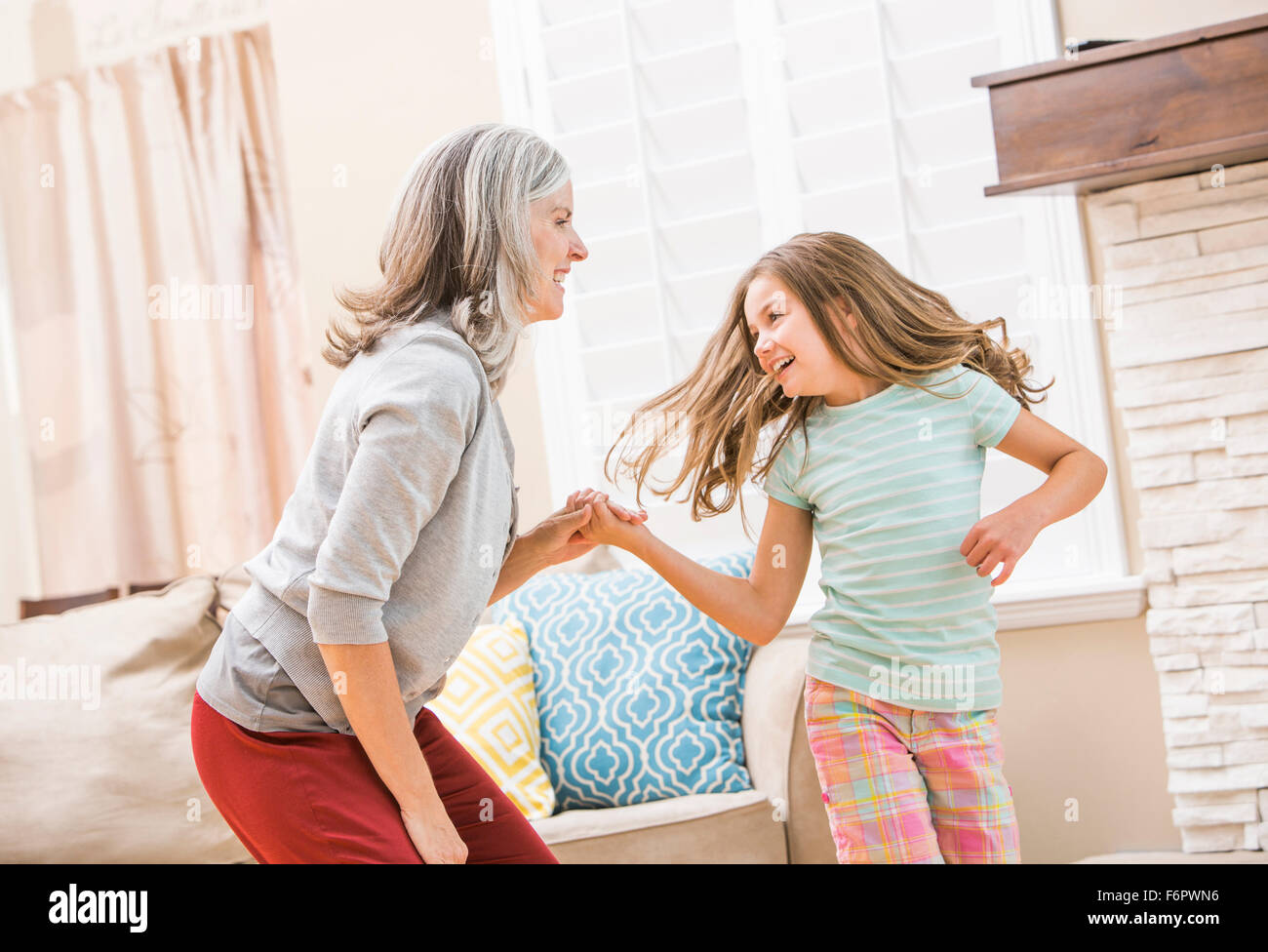 Caucasian grandmother and granddaughter dancing in living room Stock Photo