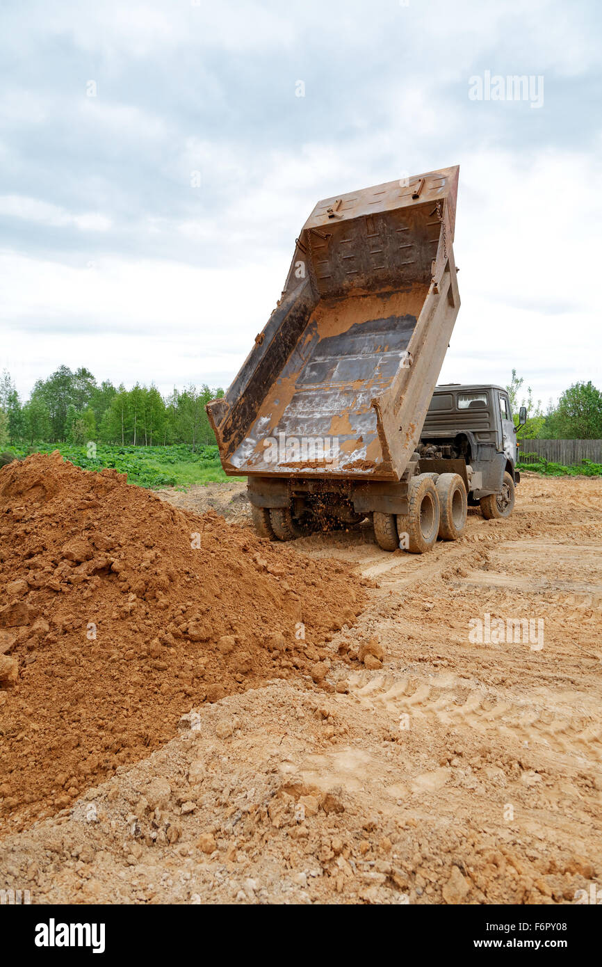 dump-body truck unloads a ground on the land Stock Photo