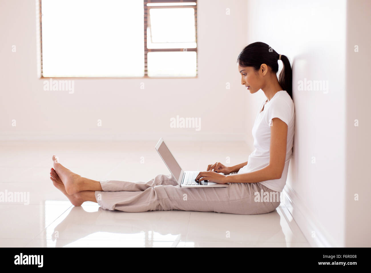 young Indian woman working on laptop computer in new house Stock Photo