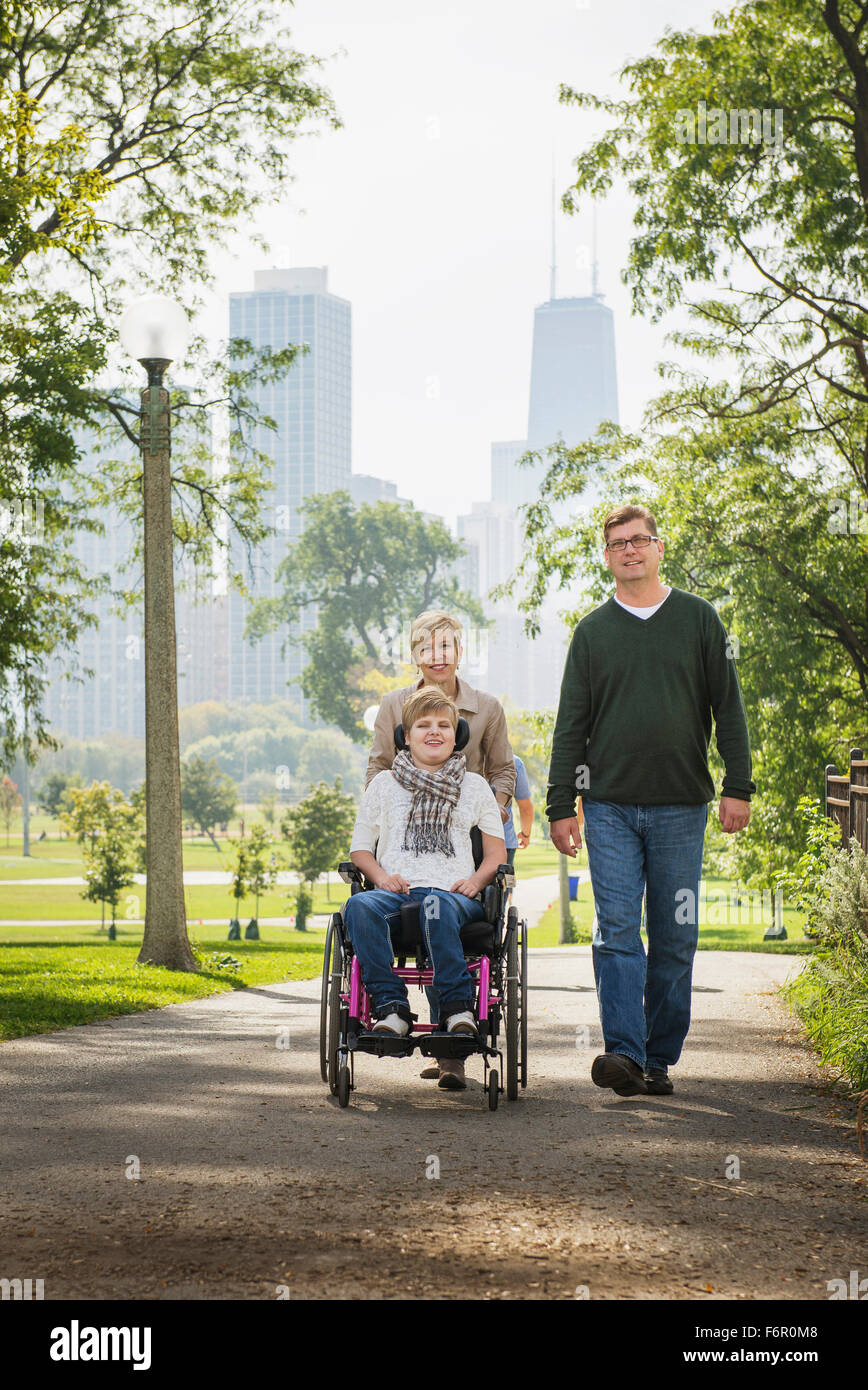 Parents pushing paraplegic daughter in wheelchair Stock Photo