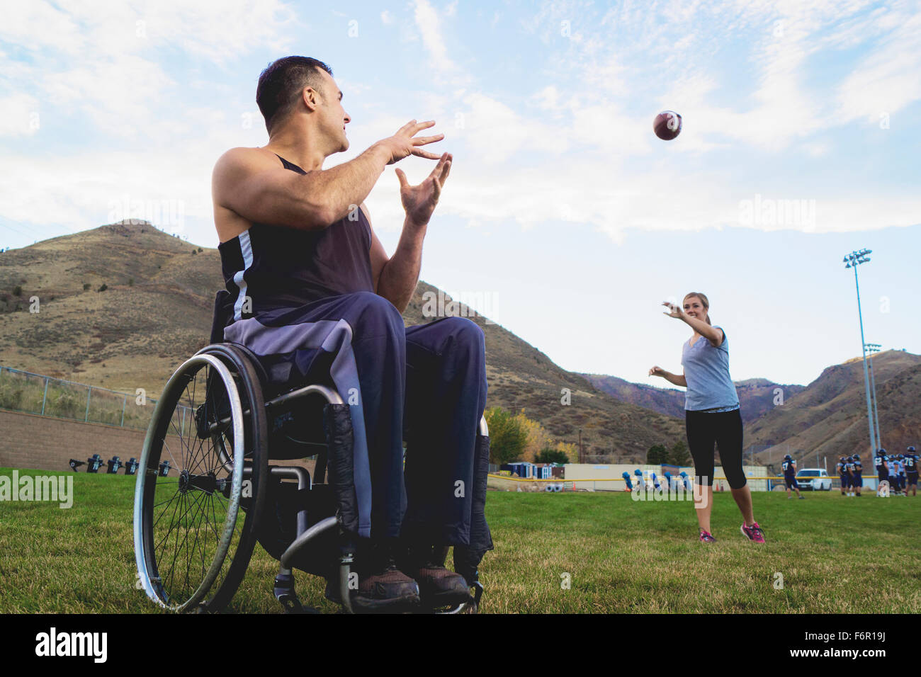 Paraplegic athlete in wheelchair with girlfriend tossing ball Stock Photo