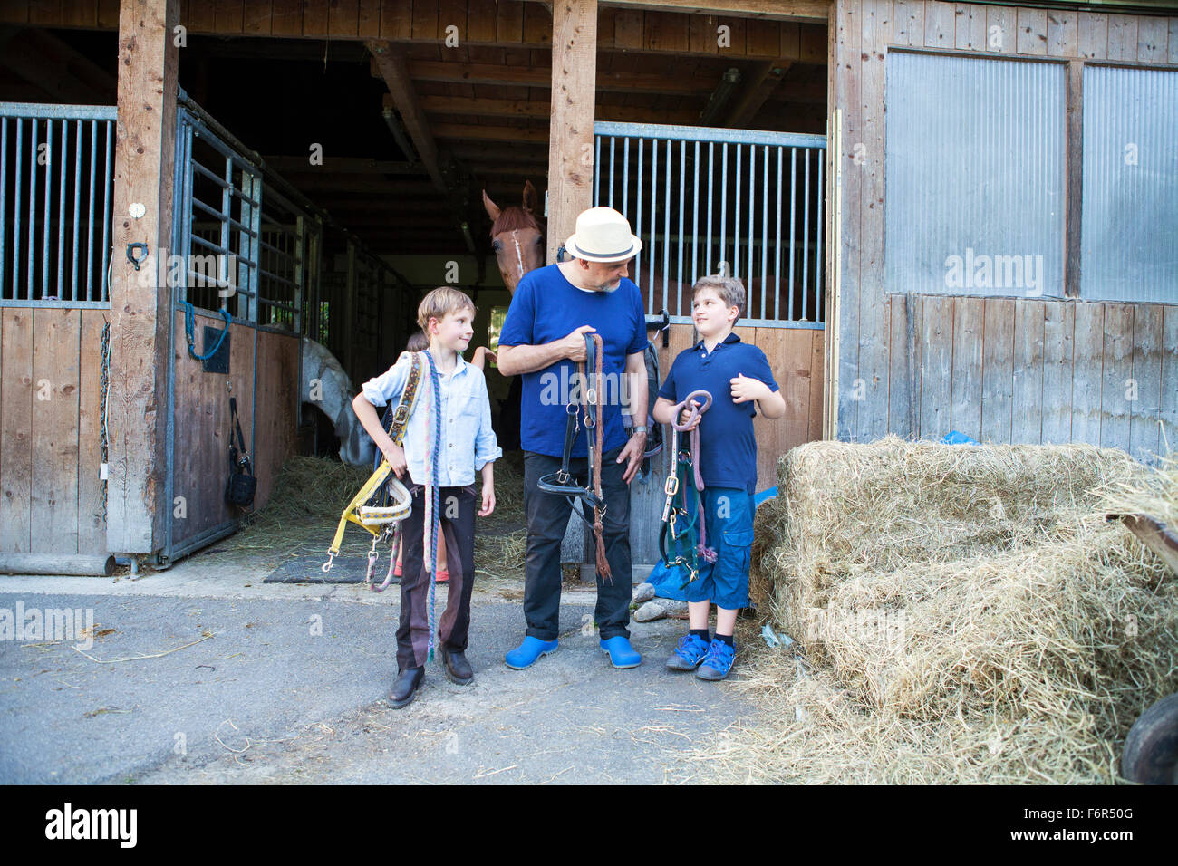 Grandfather and grandchildren in front of stable Stock Photo