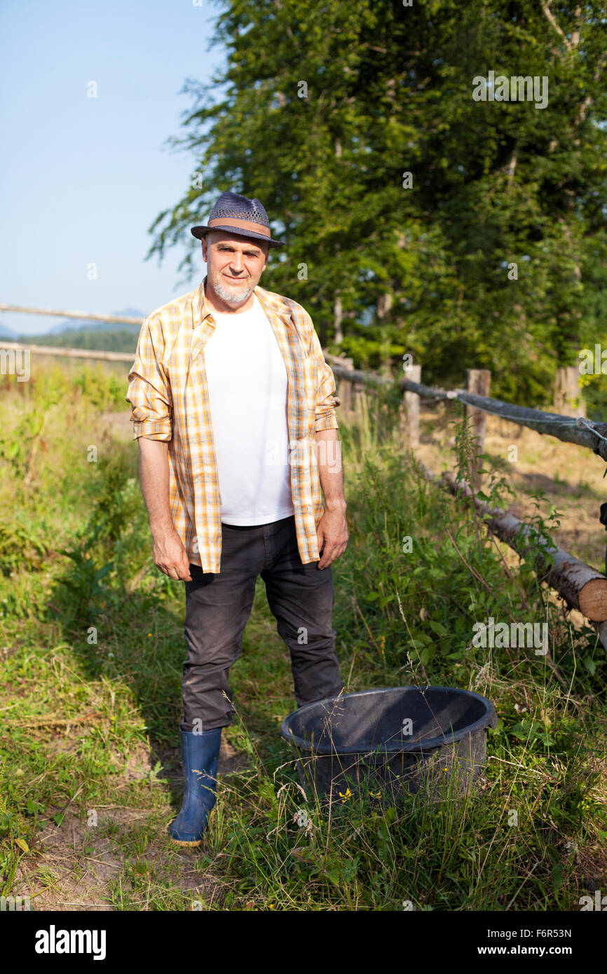 Senior man with hat standing in pasture Stock Photo
