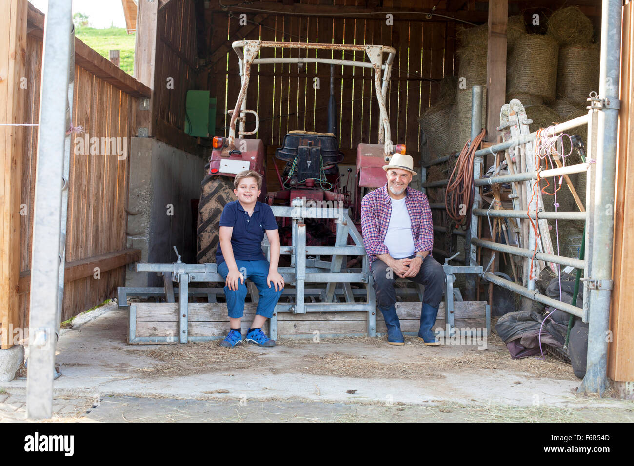 Grandfather and grandson taking a break in stable Stock Photo