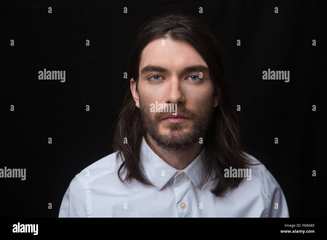 Portrait of a man with beard and long hair looking at camera isolated ...