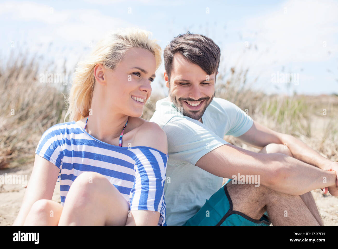 Young couple sitting side by side on beach Stock Photo