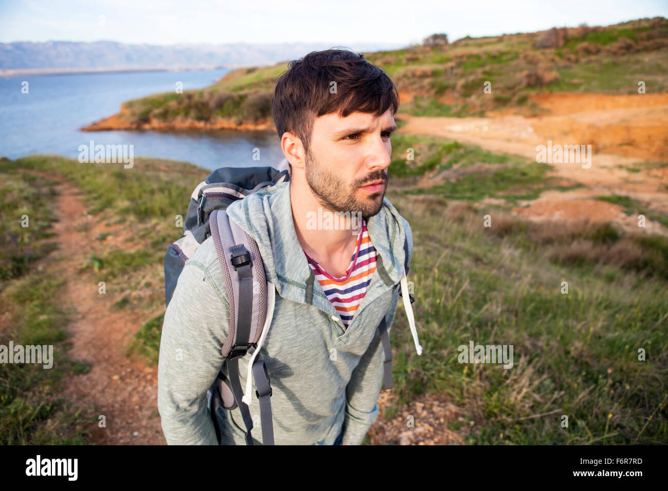 Young man hiking along coastal path Stock Photo