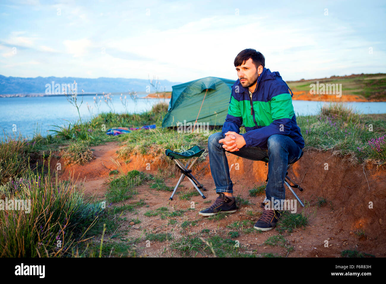 Young man at campsite day dreaming Stock Photo