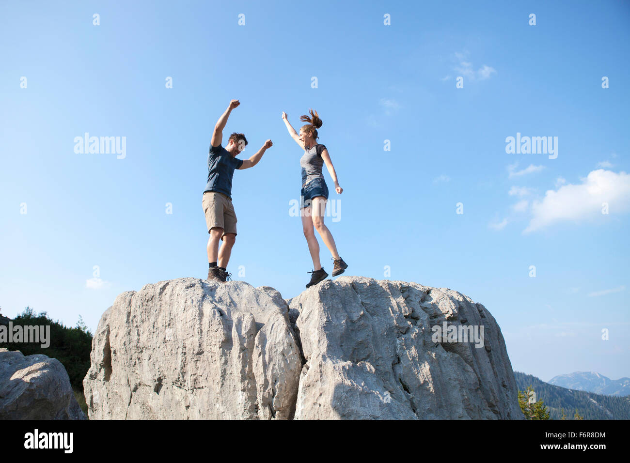 Young couple cheering on mountain peak Stock Photo