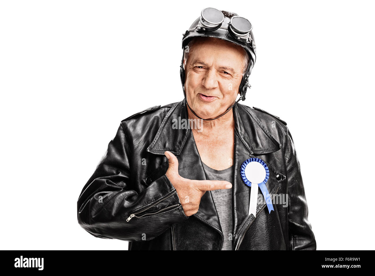 Joyful senior biker pointing towards a blue award ribbon on his black leather jacket isolated on white background Stock Photo