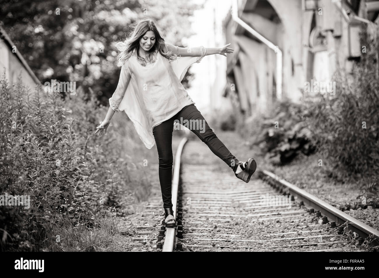 Young woman laughing, standing on train tracks Stock Photo - Alamy