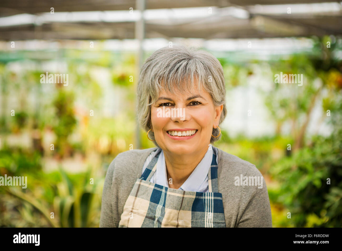 Beautiful mature woman gardening and looking at camera while smiling Stock Photo