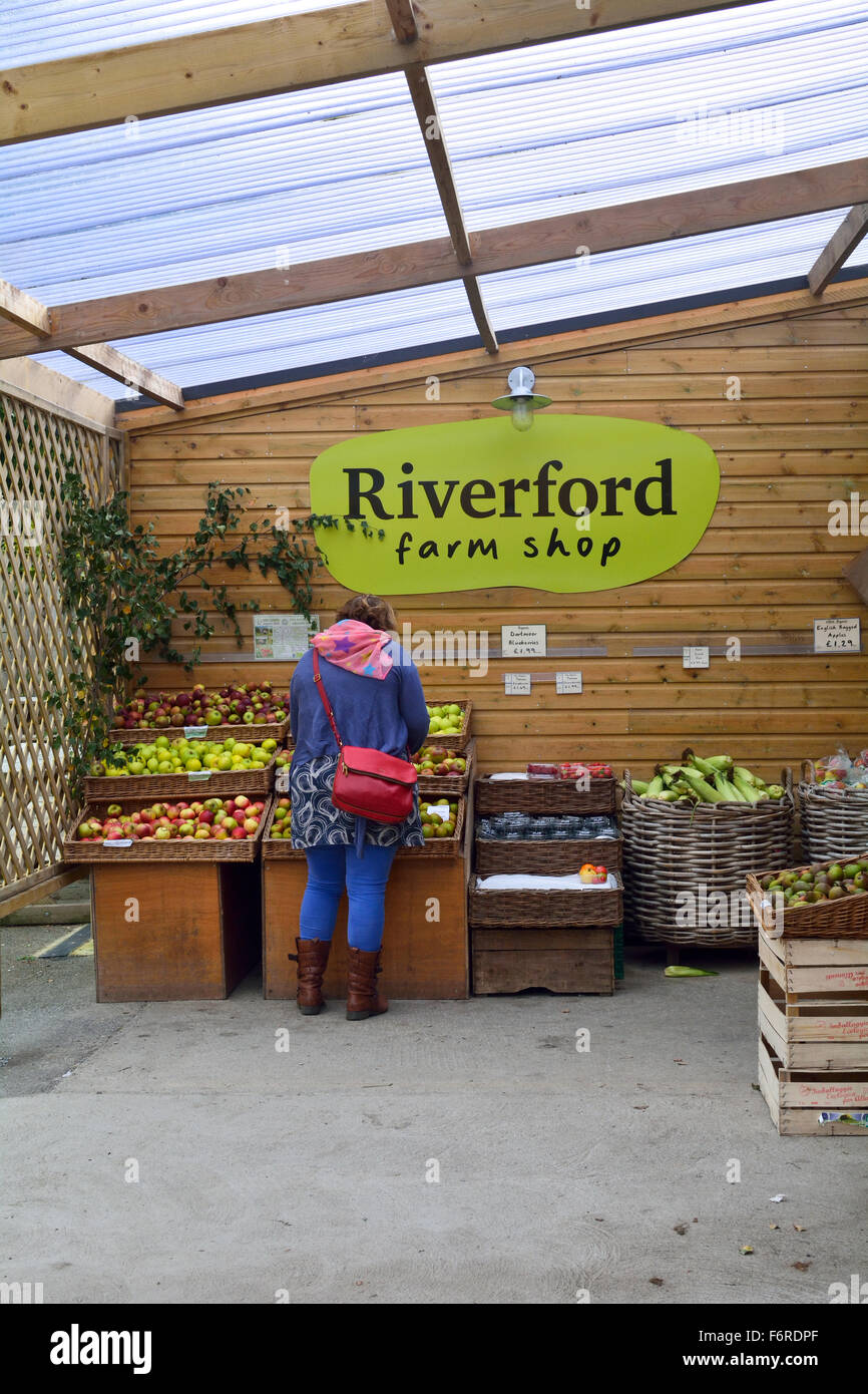 Woman selecting fruit to buy from Riverford Farm Shop sign - sellers of organic products in Devon, England Stock Photo